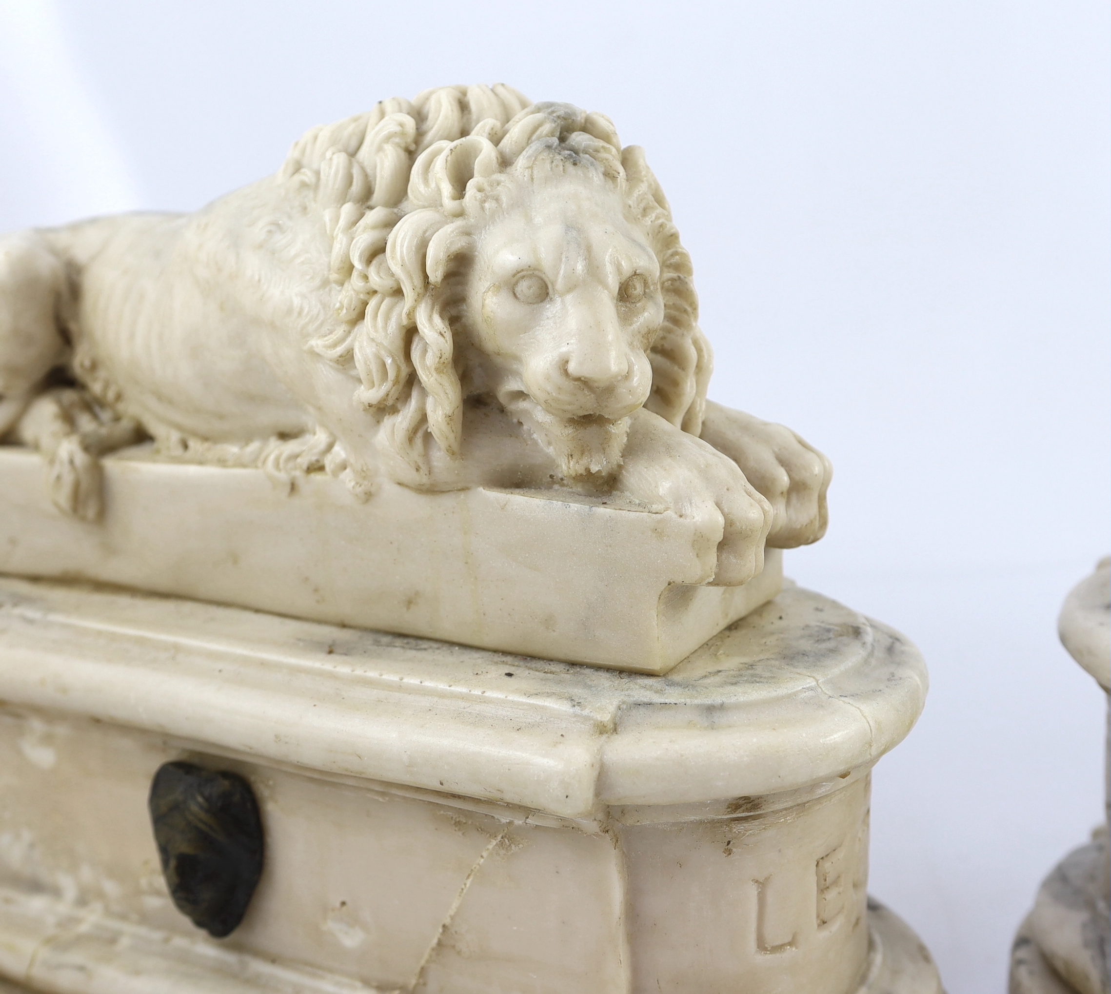 After the Antique. A pair of marble resin models of the Medici lions, each seated upon an oblong plinth, applied with bronze masks, inscribed LECXX, 41cm long, 15cm deep, 29cm high